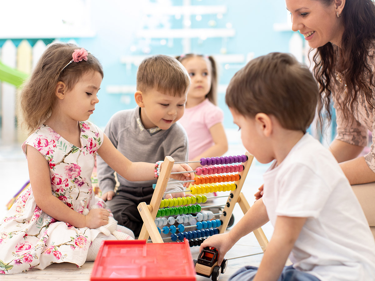 Daycare teacher helping children improve their motor skills