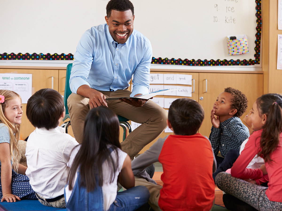 A teacher reading a book to a group of young students